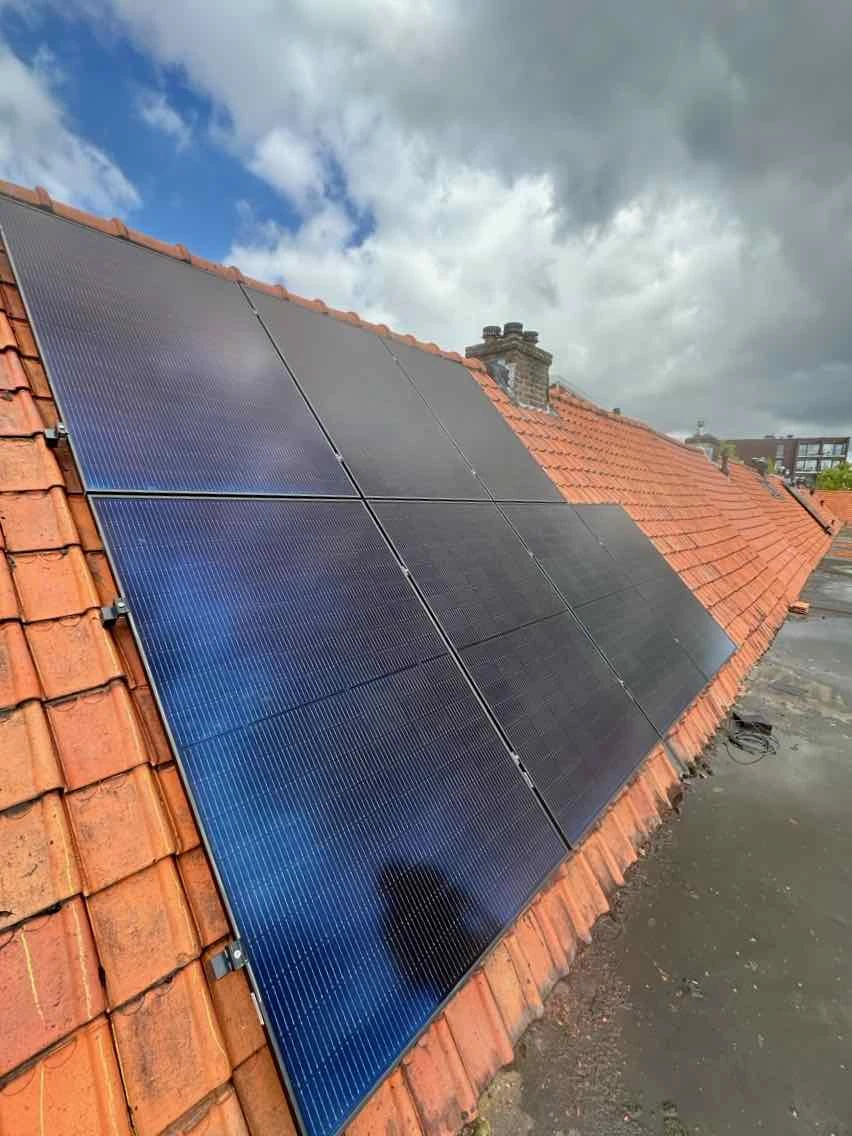 zonnepanelen op een schuin dak met donkere wolken in april 2024